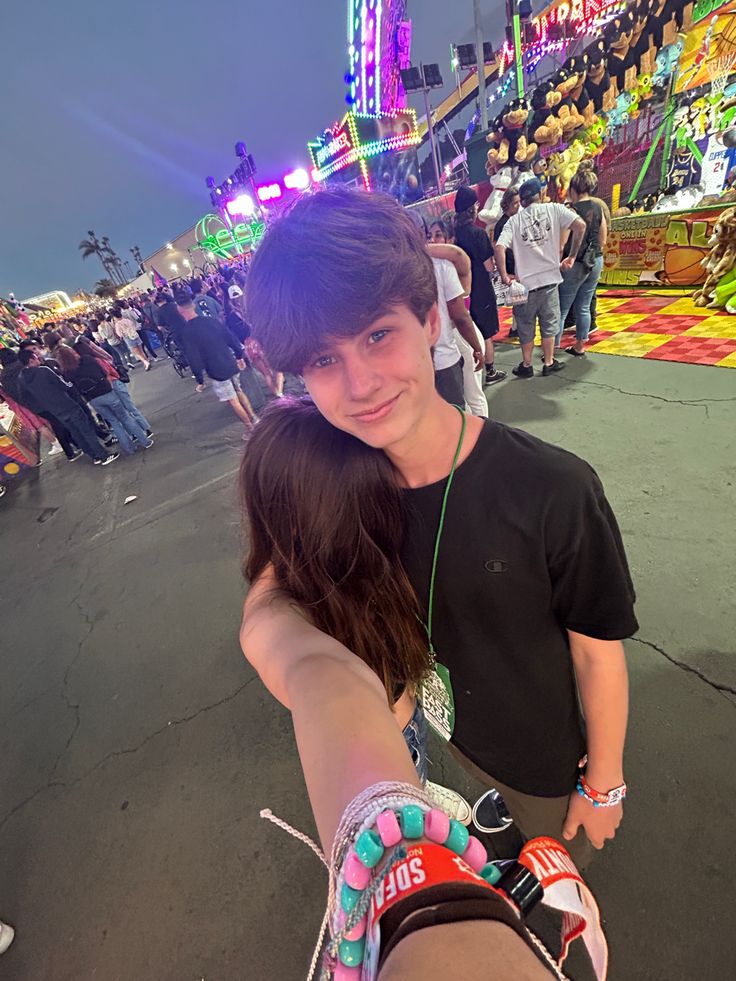 a young man and woman taking a selfie at an amusement park