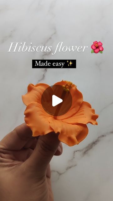 someone is holding an orange flower with the words hirscuss flower made easy