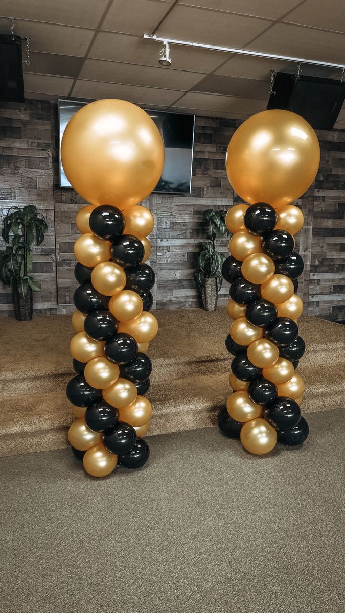 two tall black and gold balloons are on the ground