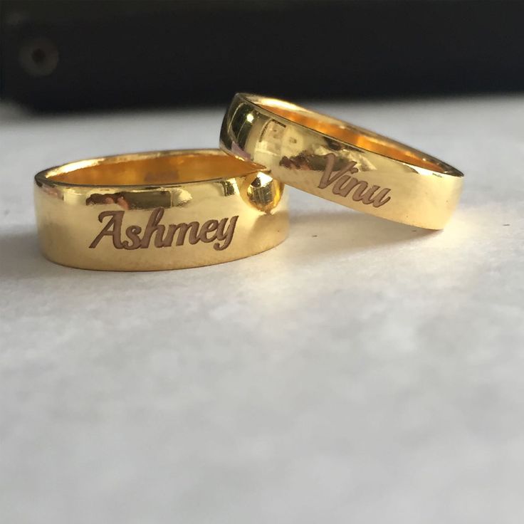 two gold wedding rings with the words ashney and you engraved on them sitting on a table