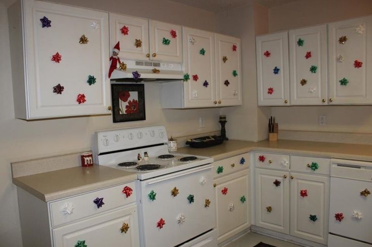 a kitchen with white cabinets and christmas decorations on the wall behind the stove top oven