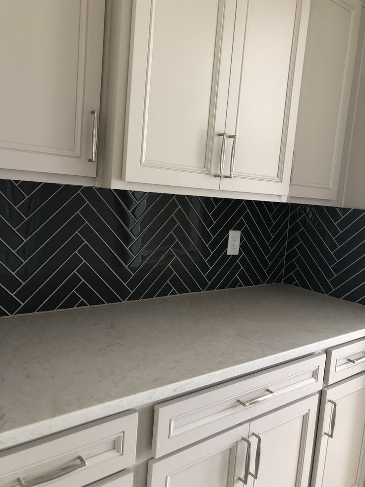 a kitchen with white cabinets and black marble counter tops on the backsplash is shown