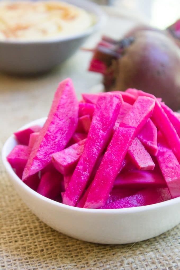 a white bowl filled with sliced up beets on top of a table next to other bowls