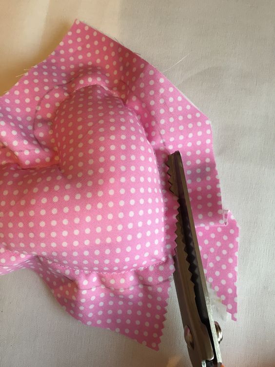 a pink and white polka dot fabric with a pair of scissors on top of it