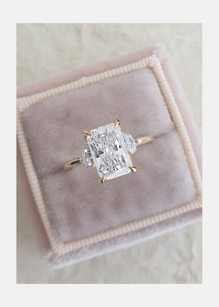 an engagement ring in a velvet box with a cushion cut diamond on the front and sides