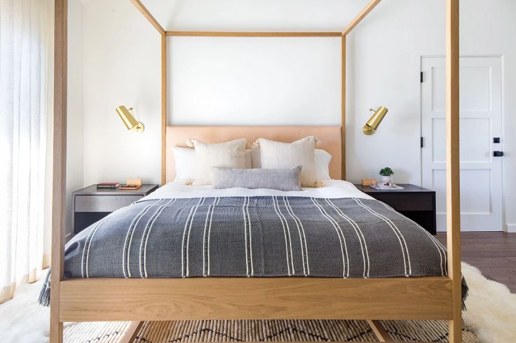 a bedroom with a four poster bed and white walls, along with rugs on the floor