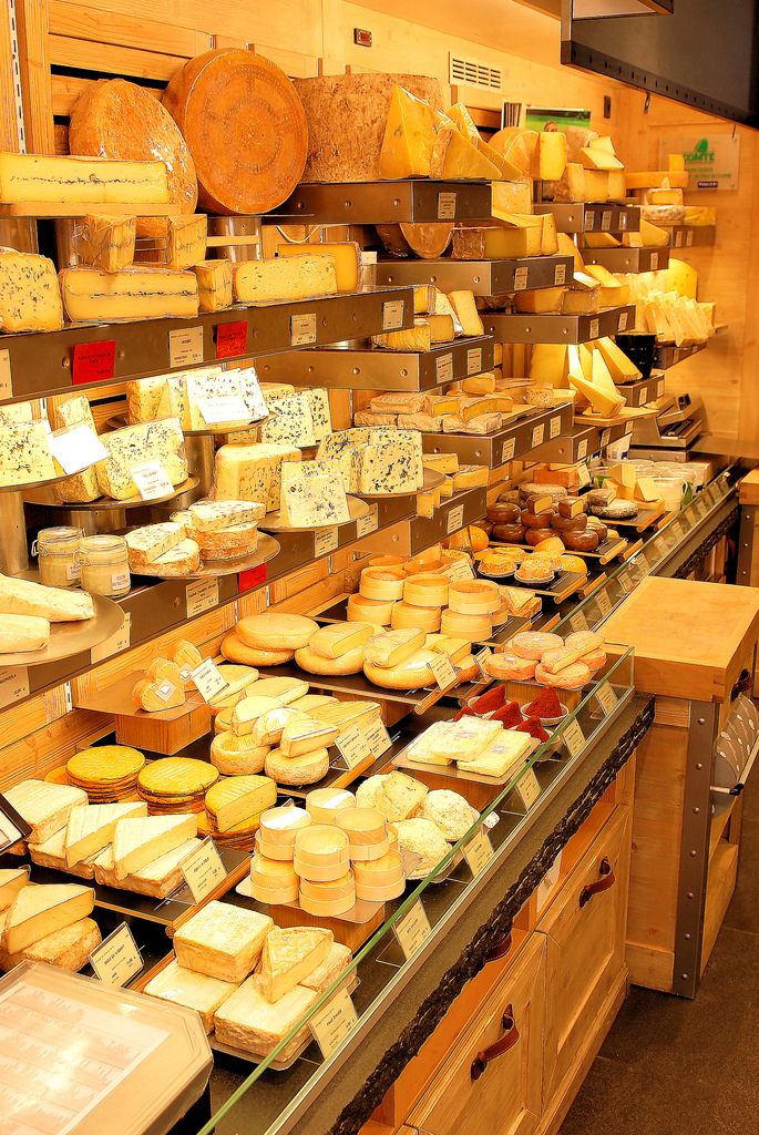 cheeses are displayed on shelves in a store