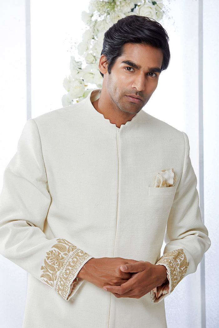 This ivory sherwani set features kiran dori embroidery on the cuffs and a stepper collar detail on a matka silk base. This ensemble is paired with a cotton silk kurta and a stretchable cotton silk trouser. Complimenting footwear is also available.From Seema Gujral's Tuscan Summer collection. DELIVERY TIMEPlease allow 8-12 weeks for your outfit to arrive.FABRIC DETAILSMatka SilkProfessional cleaning only. Cream Sherwani With Chikankari Embroidery And Long Sleeves, Cream Long Sleeve Sherwani With Chikankari Embroidery, Ceremonial Cream Nehru Jacket With Zari Work, Off White Zari Work Sets For Formal Occasions, Traditional Off White Raw Silk Bandhgala, Ceremonial Off White Sets With Resham Embroidery, Traditional Raw Silk Bandhgala In Off White, Cream Bandhgala With Chikankari Embroidery For Transitional Season, Cream Bandhgala With Chikankari Embroidery In Raw Silk