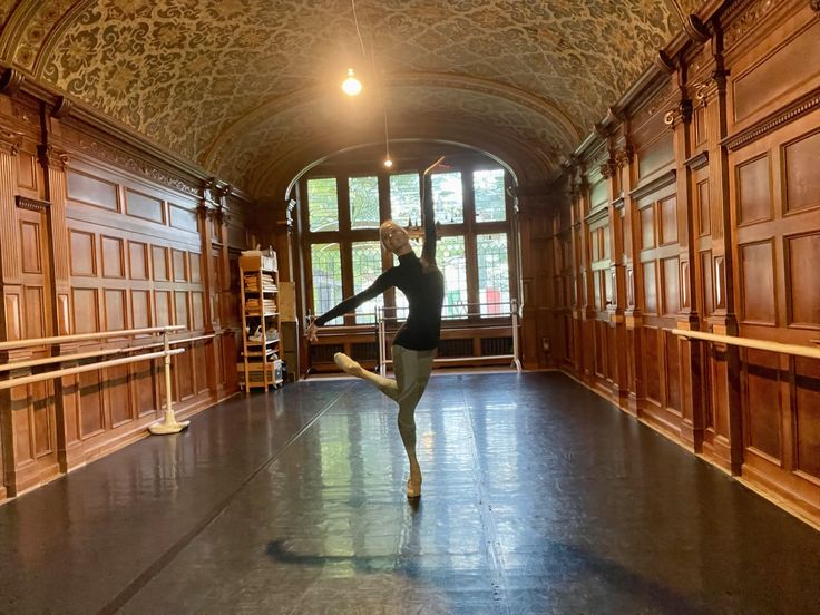 a ballerina is practicing in an ornate room with wood paneled walls and flooring