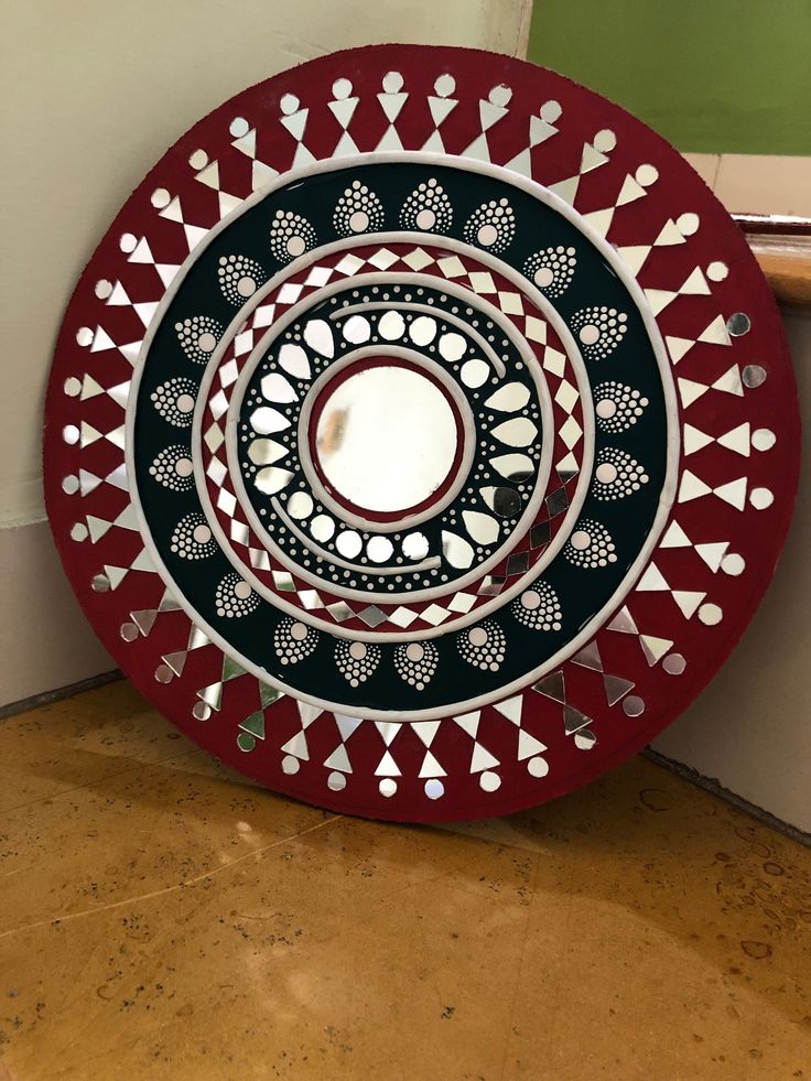 a red and black plate sitting on the floor next to a wall in a room