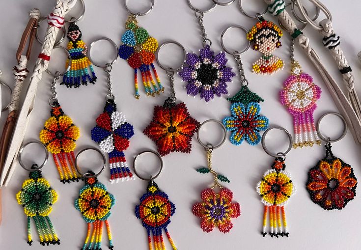 a bunch of key chains that are made to look like flowers and medallions with beads on them