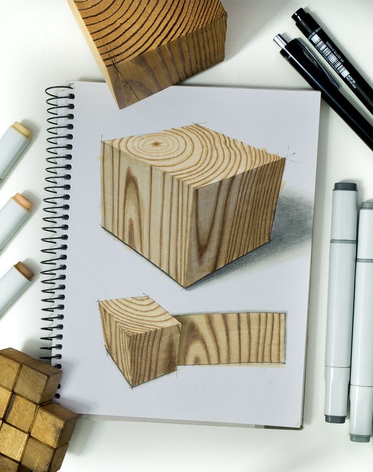 two wooden blocks on top of a notebook next to pens and pencils