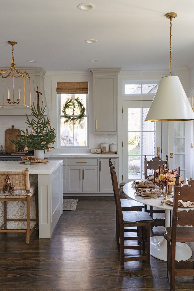 a dining room table and chairs in a large kitchen with white cabinets, wood flooring and wooden floors