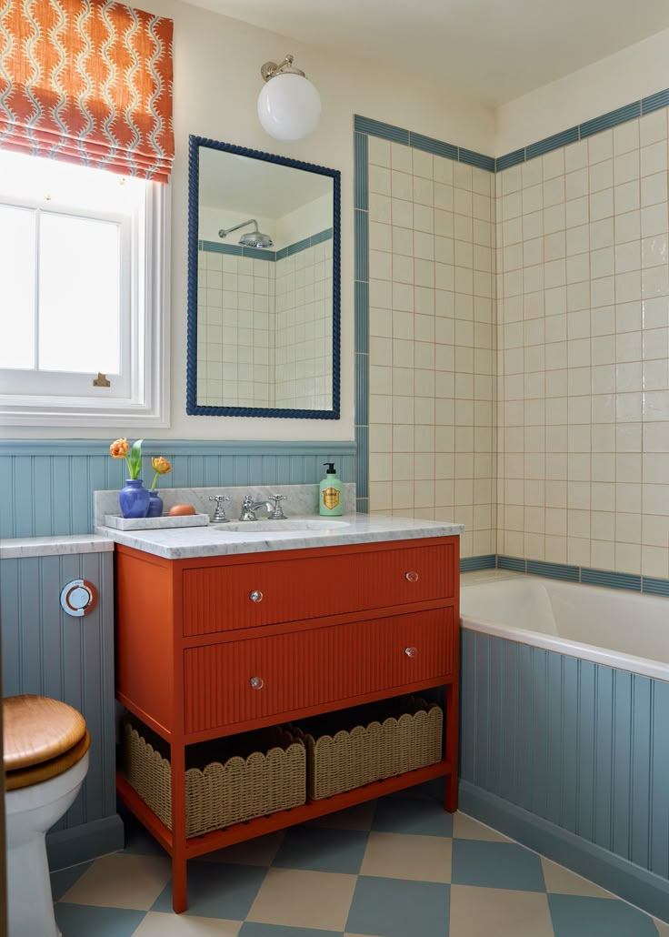 a bathroom with blue and white walls, checkered flooring and a red cabinet