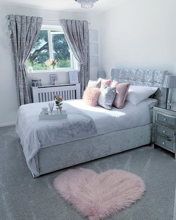 a bedroom with a bed, nightstands and pink fur rug on the floor in front of a window