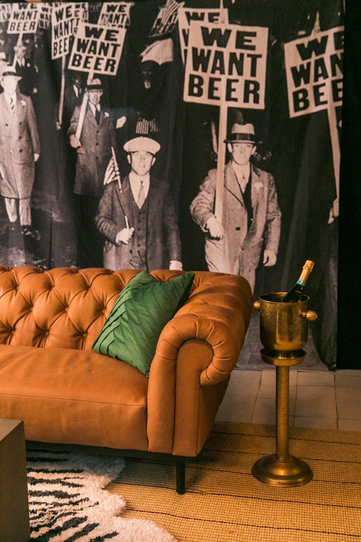 an orange couch sitting in front of a black and white wall with posters on it