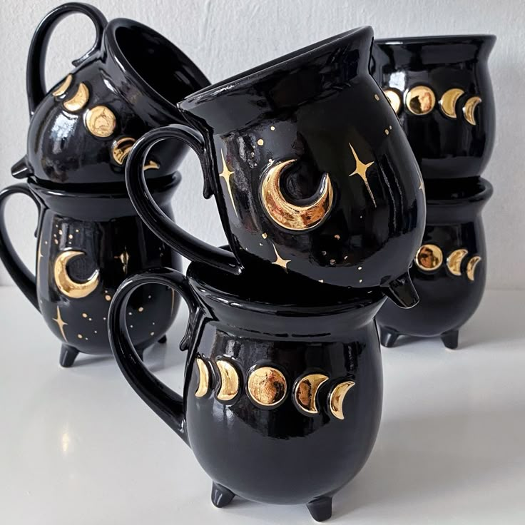 four black and gold coffee mugs sitting next to each other on a white surface