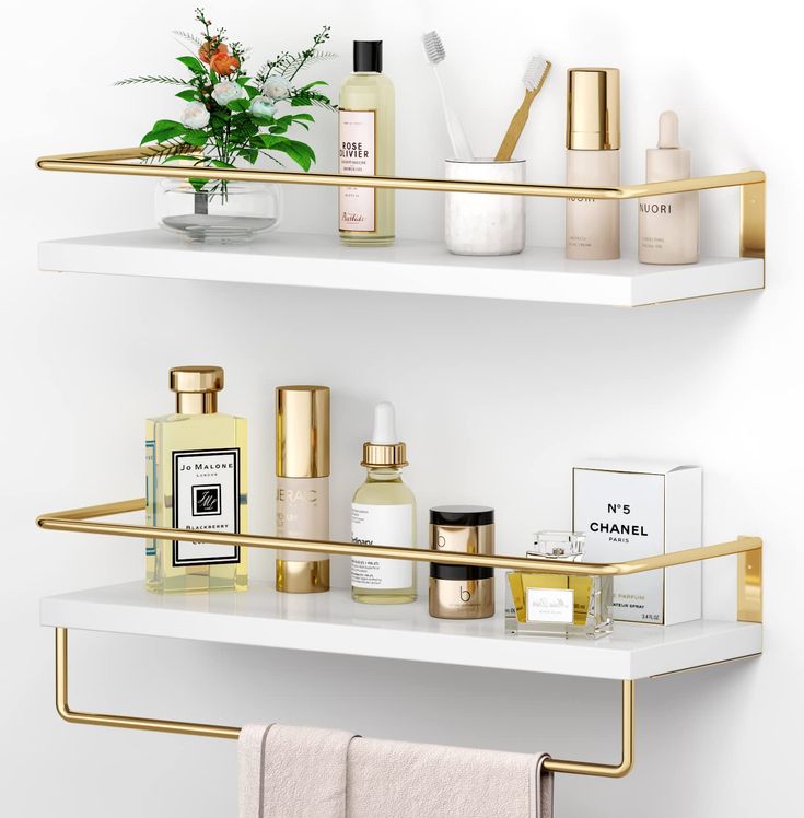 two white shelves with gold trim holding personal care items and a potted plant on one shelf