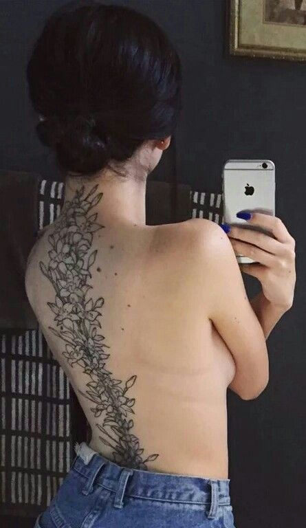 a woman with a tattoo on her back taking a selfie