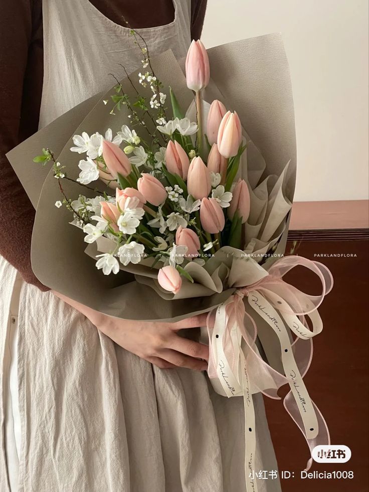 a woman holding a bouquet of pink and white flowers