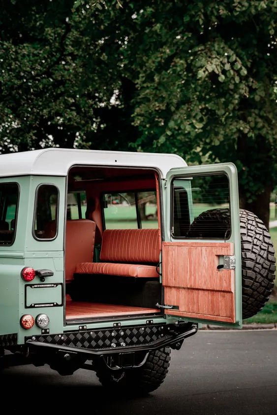 an old green truck parked on the side of the road with its door open and seat up