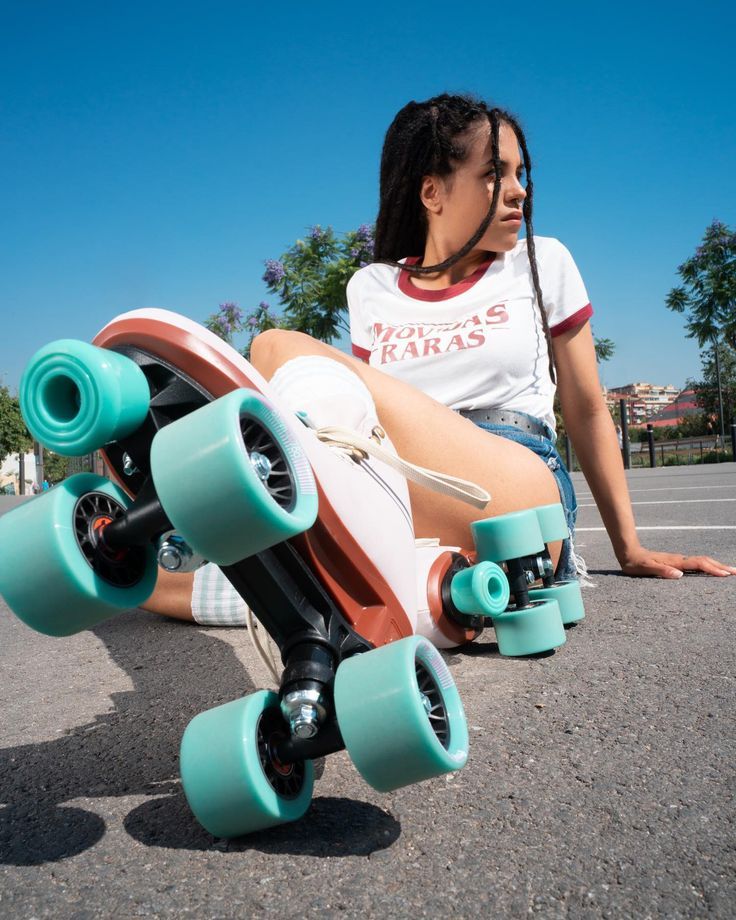 a young woman sitting on the ground with her skateboard in front of her feet