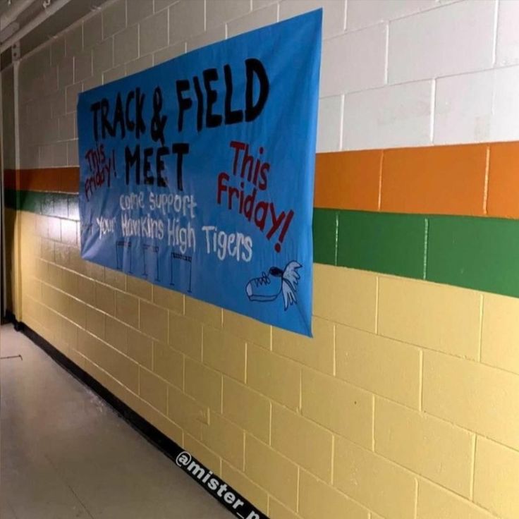 there is a sign that says track and field next to the wall in this hallway