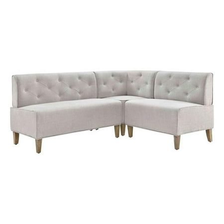 a white sectional couch with wooden legs and buttons on the back, sitting against a white background