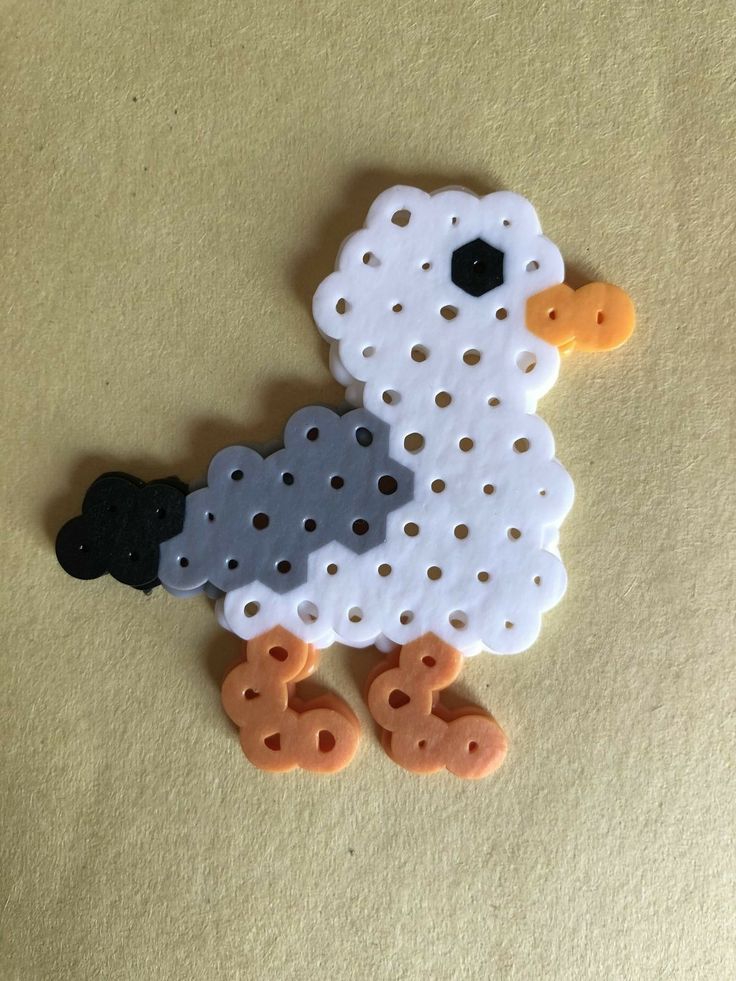 a white and black sheep brooch sitting on top of a yellow table next to two orange buttons