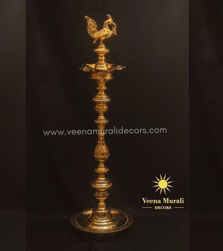 a golden metal candle holder with a rooster on it's top and the words veena muraii written in arabic