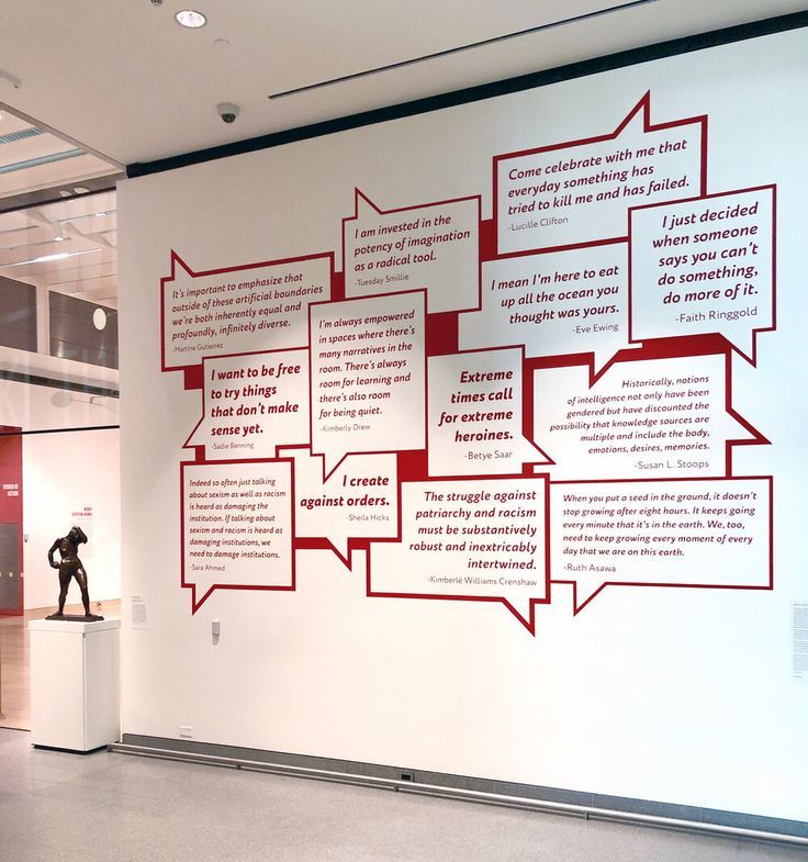 a man standing in front of a white wall with red words on it