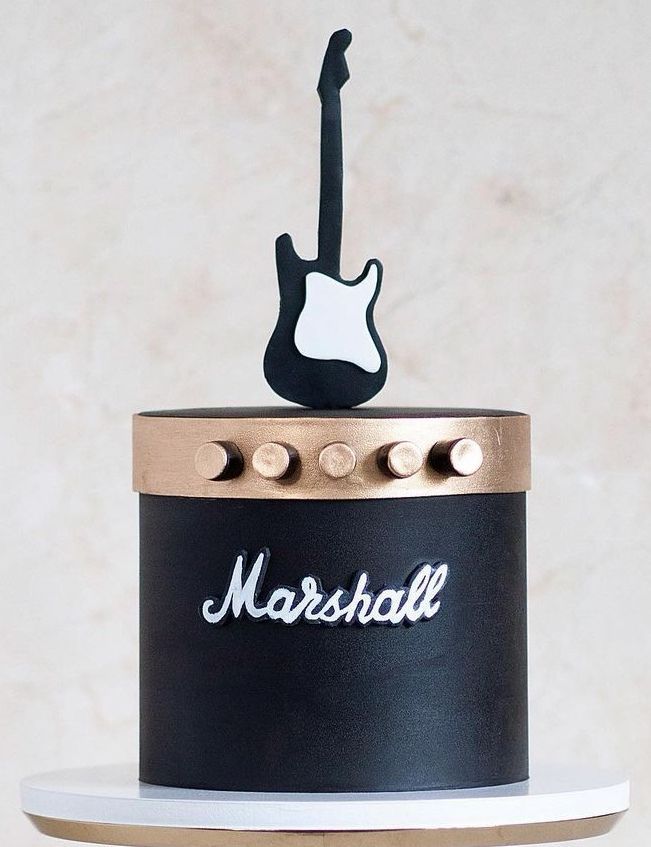 there is a black and gold cake with a guitar decoration on the top that says marshall