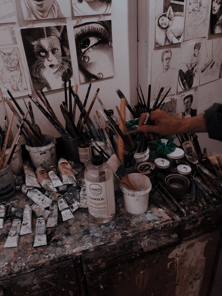 an artist is painting on the wall in his studio with lots of paintbrushes