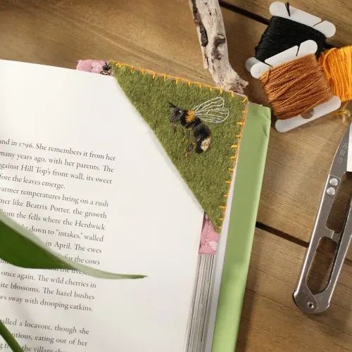 an open book sitting on top of a wooden table next to scissors and yarns