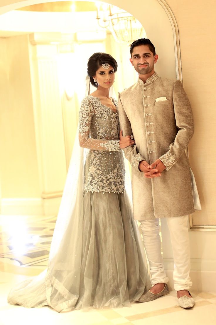 a man and woman standing next to each other in front of a mirror wearing wedding attire