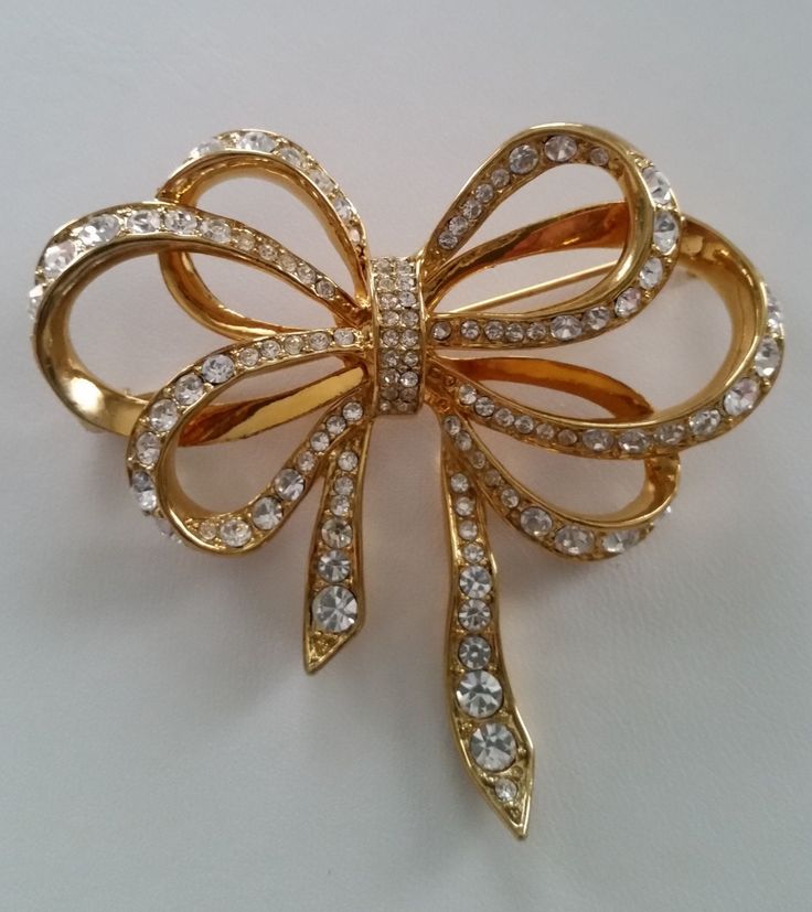 Brilliant KENNETH J LANE Diamanté Crystal Ribbony Bow Brooch Gold Plated Authentic Collectible Designer Vintage Luxury Costume Jewelry... This Beautifully Brilliant Bow brooch hails from Iconic Designer Kenneth J Lane. Signed KJL this Graceful Multi Ribbon Bow design figural is a Stunning example of this Beloved Designer's Extraordinary work. It's a Dazzlingly Feminine piece consisting of row after row of Pavé encrusted Sparkling Diamanté Crystal rhinestones set in a Gleaming Gold plated finish. It's a Classic Beauty with a Wonderful sense of Flowing Movement. Elegant Bows and Pearls take center stage in 2024 bringing this Timeless Beauty to the Forfront of Tastefully Appointed Style. As A Designer Kenneth J Lane captivated the likes of Elizabeth Taylor, Jackie Kennedy Onassis and Princess Ribbon Brooch, Avon Vintage, Walmart Jewelry, Bow Brooch, Vintage Ribbon, Antique Brooches, Bow Jewelry, Designer Vintage, Bow Design