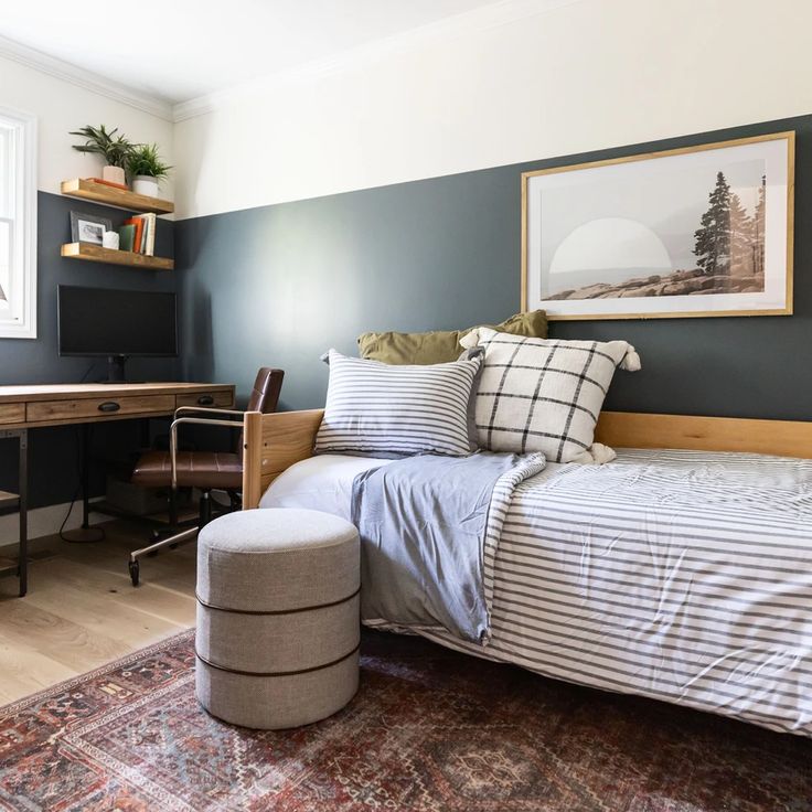 a bedroom with a bed, desk and chair next to a painting on the wall