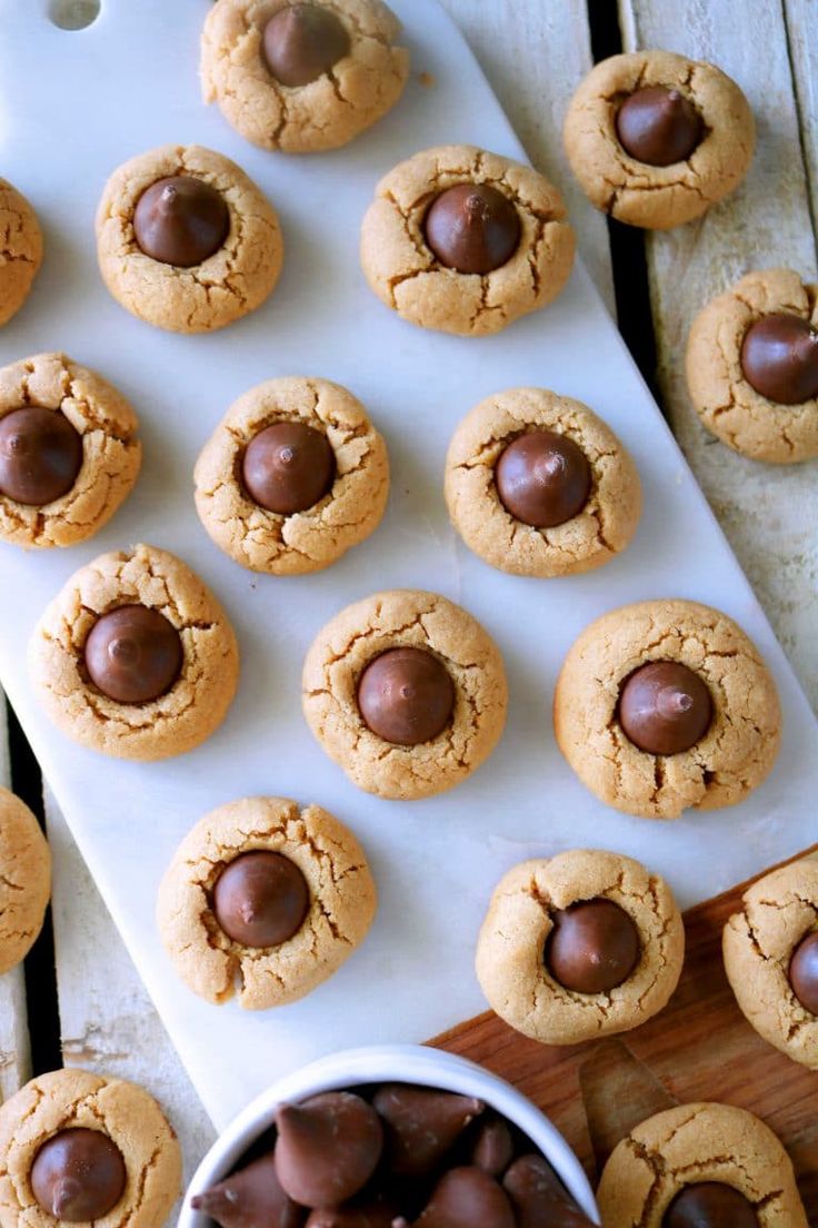 peanut butter chocolate chip cookies on a cutting board next to a bowl of chocolate chips