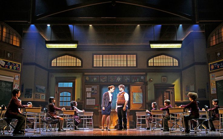 a group of people standing on top of a stage next to each other in front of chairs