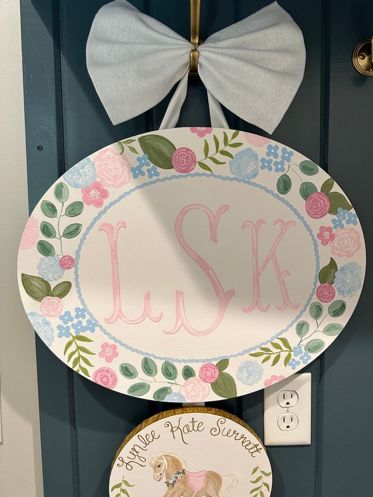 two plates are hanging on the front door and one is decorated with a dog's name