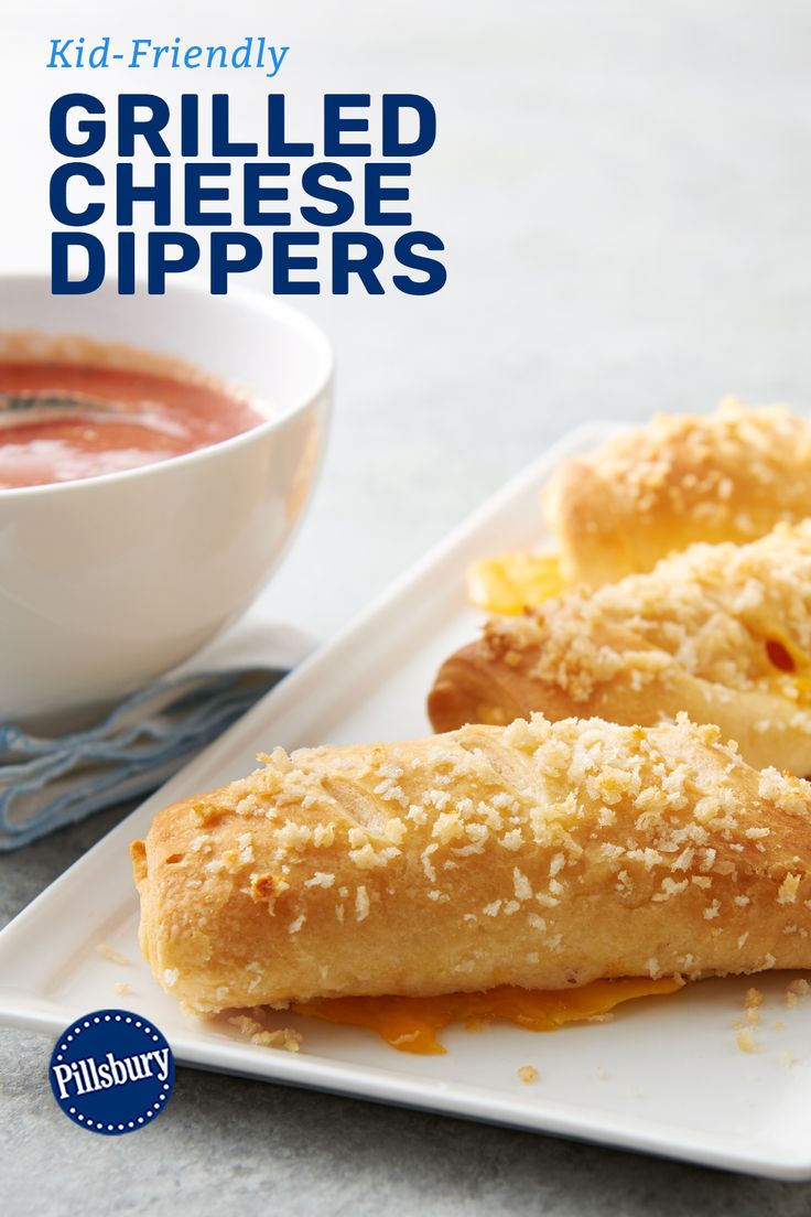 two grilled cheese dippers on a white plate next to a bowl of soup