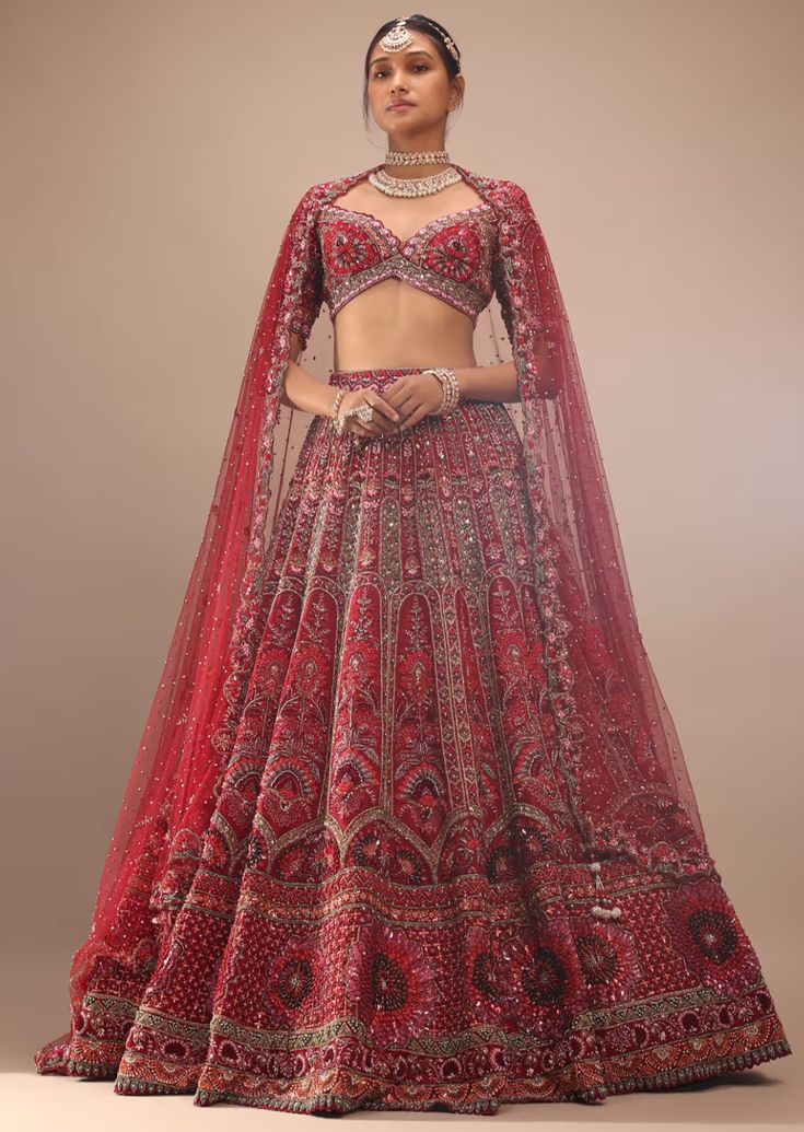 Dark red lehenga with a crop top in royal heritage embroidery.The lehenga comes in multi-color sequins, cut dana, stones, french knots 3D floral motifs embroidery, orange sequins, moti, and cut dana in half circle motifs, green cut dana, and stones in leaf shape motifs embroidery all over in kali design. The whole design is called embossed embroidery. The crop top comes in a plunging scalloped neckline with half sleeves and moti and beads fringes at the hemline. Dark Red Lehenga, Kali Design, Embossed Embroidery, Motifs Embroidery, Scalloped Neckline, Red Lehenga, Embroidered Lehenga, French Knots, Western Wedding