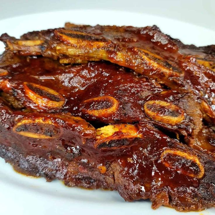 ribs covered in bbq sauce on a white plate