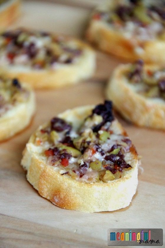 small pieces of bread with various toppings sitting on a cutting board