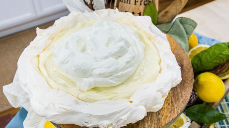 a cake sitting on top of a wooden plate covered in frosting and lemons