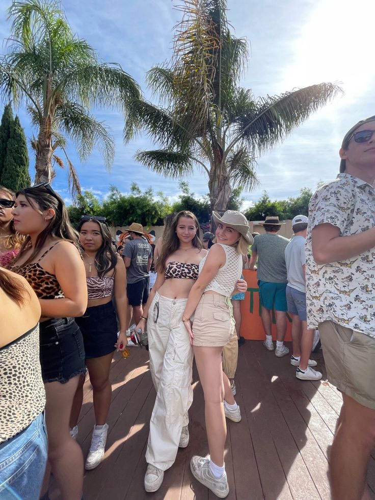 a group of people standing on top of a wooden floor next to each other in front of palm trees