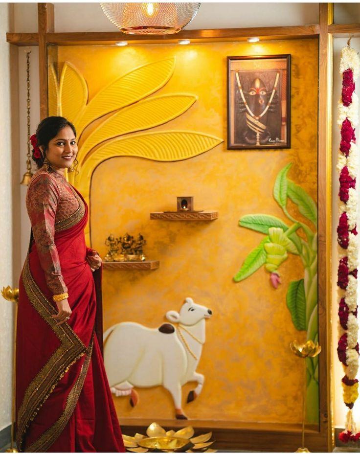 a woman in a red sari standing next to a wall with paintings on it