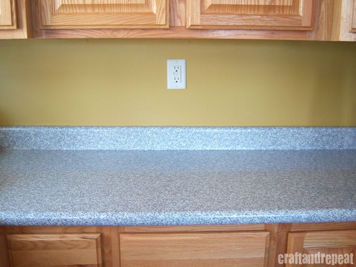 a counter top in a kitchen with wooden cabinets and cupboards behind it that has a light switch on the wall