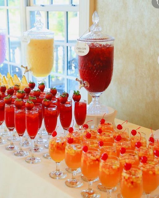 a table topped with lots of glasses filled with different types of drinks and desserts