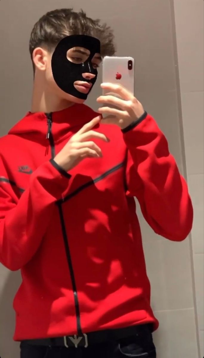 a man in a red hoodie is taking a selfie with his cell phone